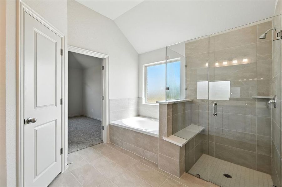 Bathroom with vaulted ceiling, a shower stall, a bath, and light tile patterned floors Bathroom with vaulted ceiling, a shower stall, a bath, and light tile patterned floors