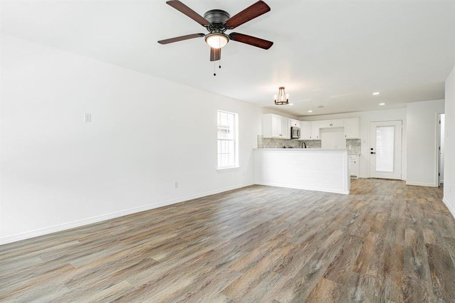 Unfurnished living room with light wood-type flooring and ceiling fan