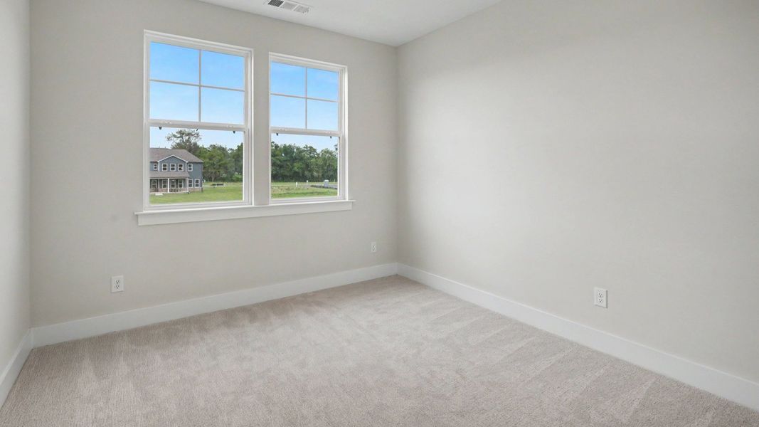 Secondary bedroom with windows and carpet