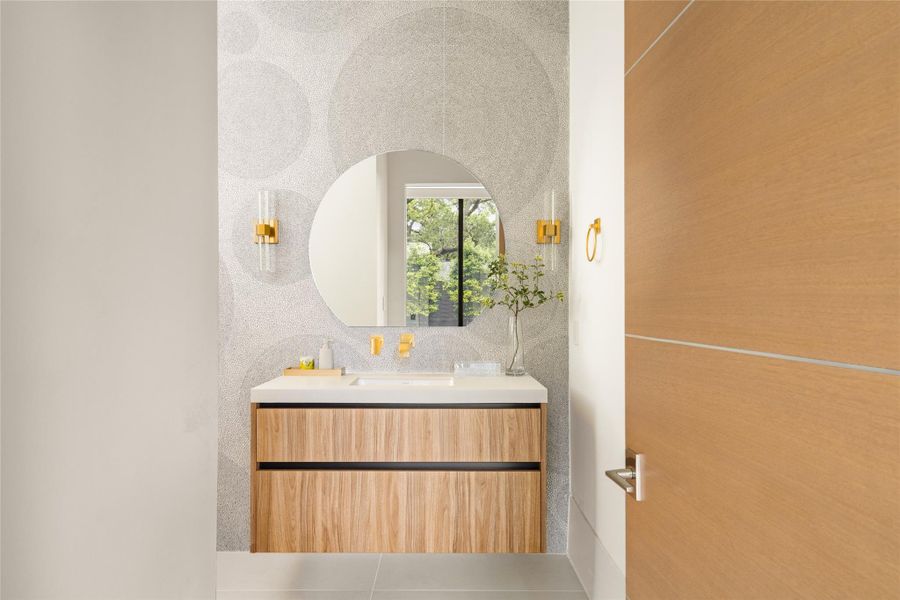 Stylish powder bath featuring a floating wood vanity, textured wall finish, and warm brass fixtures.