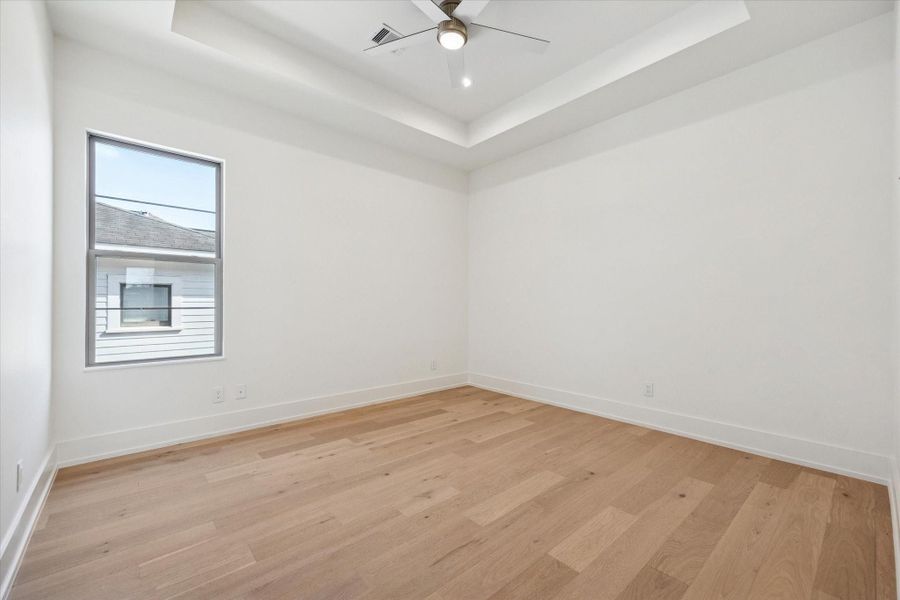 Third bedroom with a tray ceiling, recessed lighting, a walk-in closet with built-ins and an ensuite bathroom.