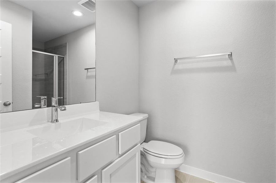 This secondary bath has private access to the front secondary bedroom. It features tile flooring, shower with tile surround, white stained wood cabinets, beautiful light countertops, mirror, sleek fixtures and modern finishes.