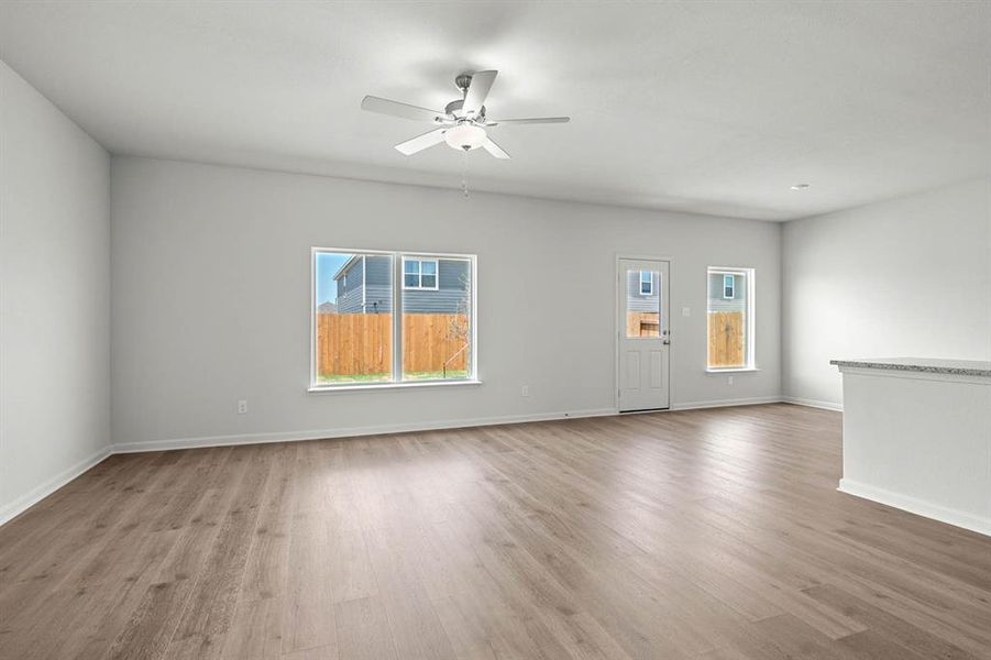 Unfurnished living room with light wood-style floors, plenty of natural light, and a ceiling fan