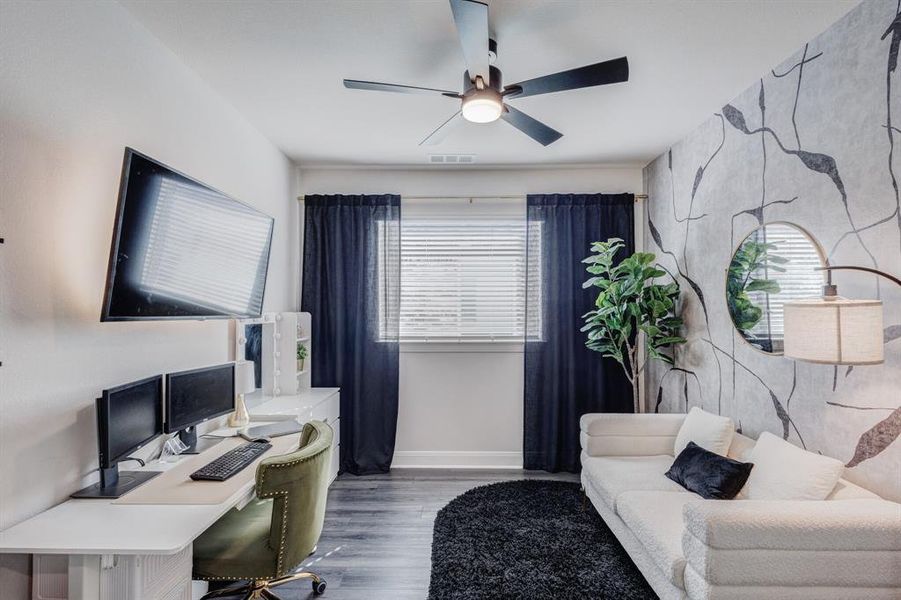 Office area with an accent wall, a ceiling fan, and wood finished floors