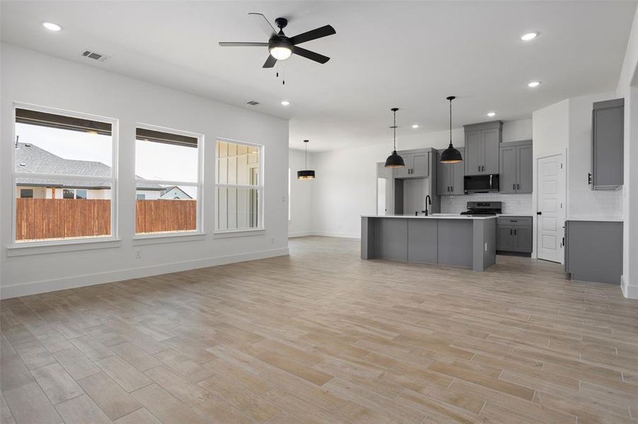 Kitchen with gray cabinets, tasteful backsplash, an island with sink, sink, and appliances with stainless steel finishes