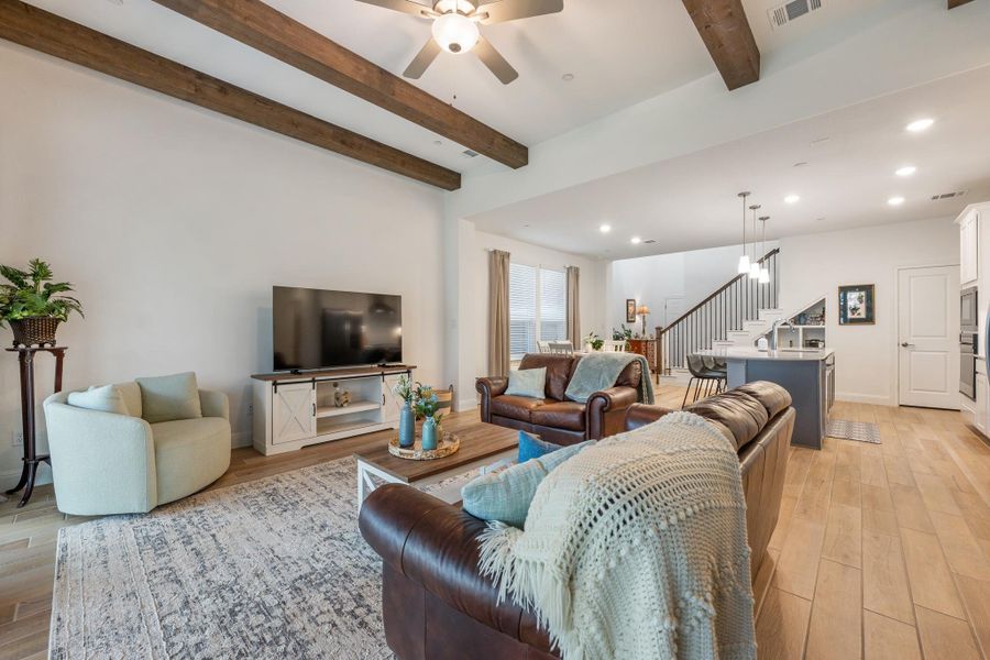 Exposed beams and recessed lighting illuminate this open-concept living space, seamlessly connecting to the kitchen and dining area. Exposed beams and recessed lighting illuminate this open-concept living space, seamlessly connecting to the kitchen and dining area.
