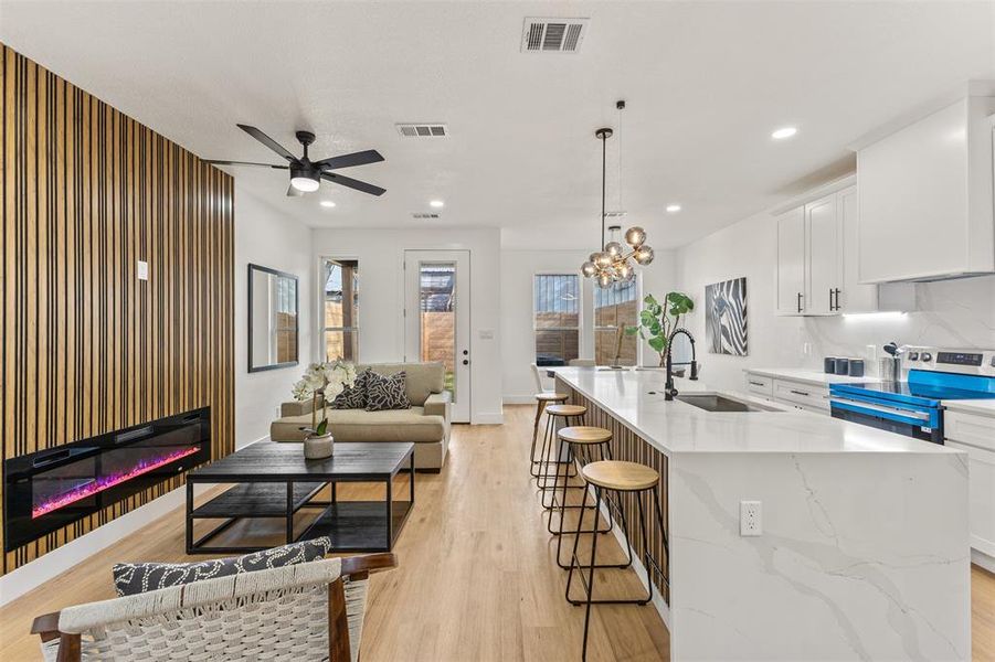 Kitchen with white cabinets, stainless steel range with electric cooktop, light stone countertops, and a chandelier