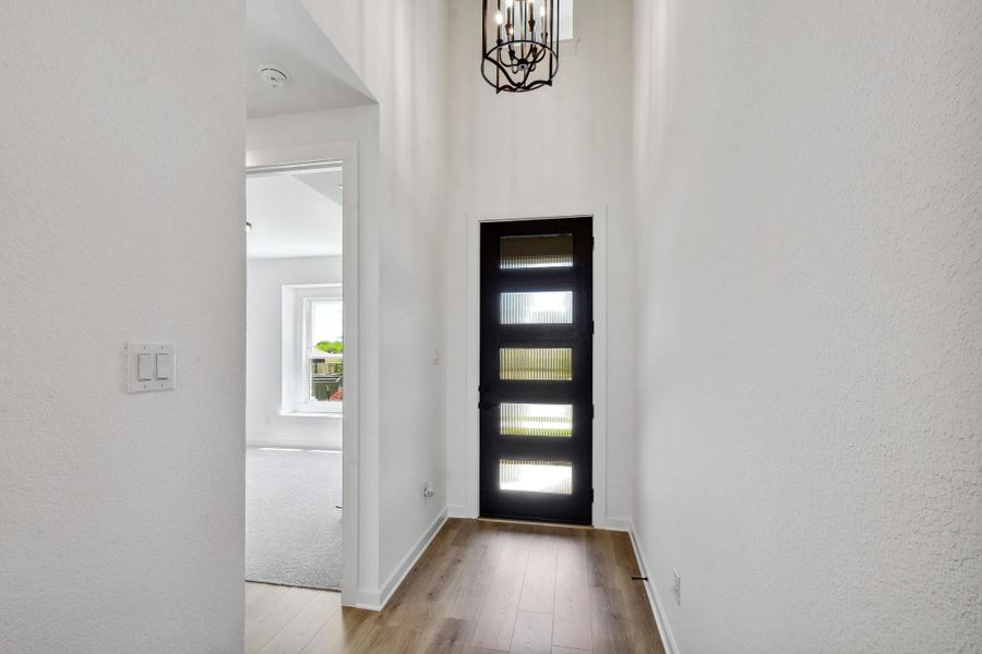 Foyer entrance with a chandelier, wood-type flooring, and a textured wall