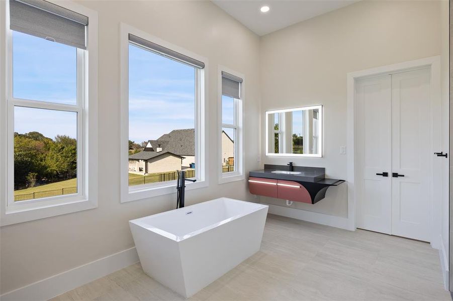 Bathroom with a tub to relax in, a wealth of natural light, and sink