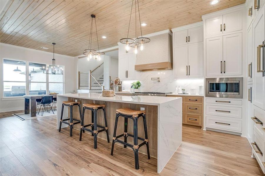 Kitchen with tasteful backsplash, wooden ceiling, a chandelier, white cabinets, and hanging light fixtures