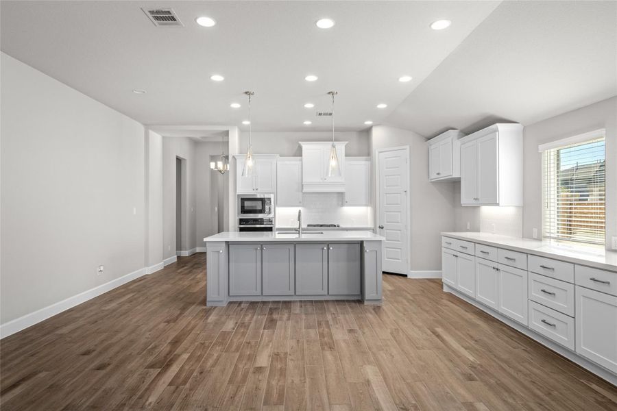 Gourmet Kitchen featuring crisp white cabinetry, stunning Granite Countertops, and a massive island.