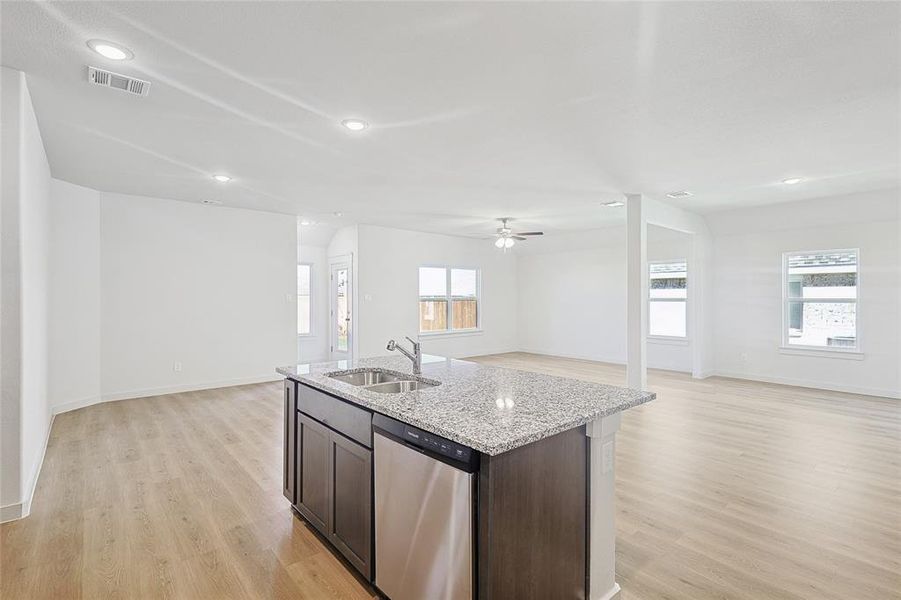 Kitchen featuring dishwasher, sink, ceiling fan, light hardwood / wood-style floors, and light stone counters