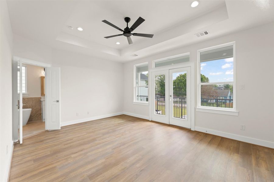 Bright and spacious bedroom, large windows offering plenty of natural light. Features French doors leading to a balcony and an en-suite bathroom with modern fixtures.