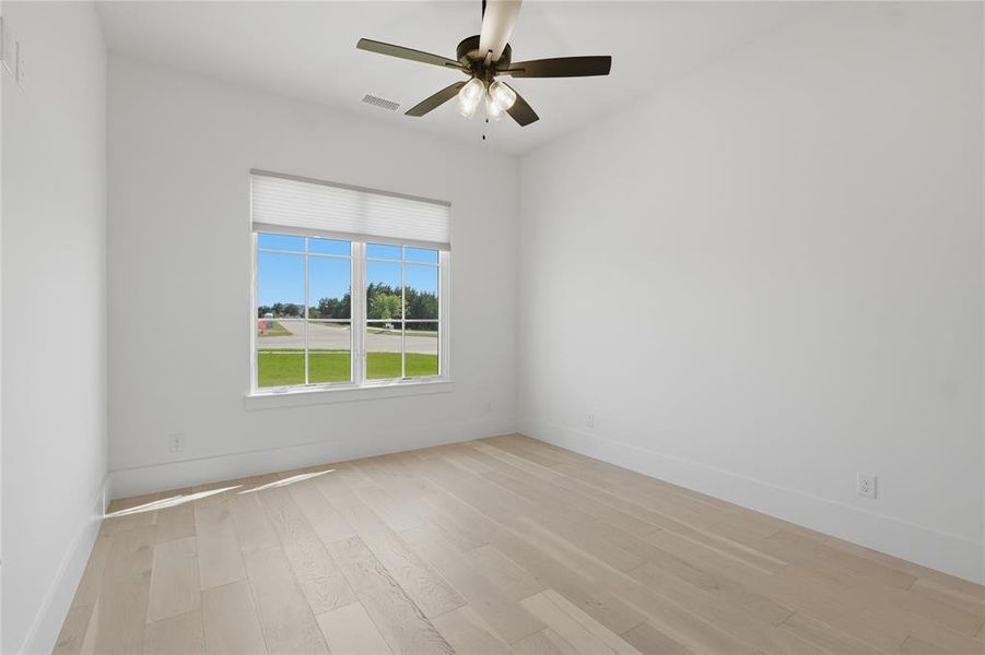Light-filled room featuring wood-finish flooring, white baseboards, a ceiling fan, and a large window with blinds
