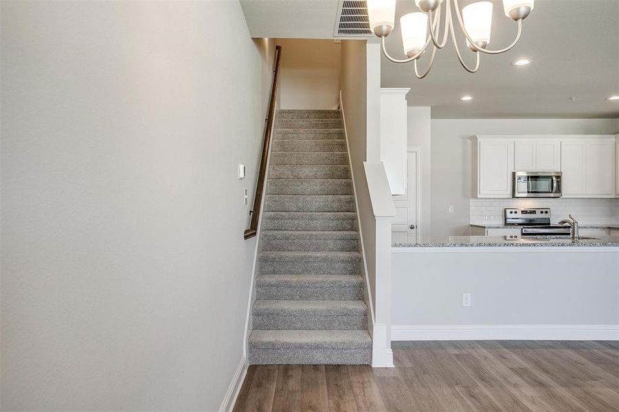 Staircase with wood finished floors and a chandelier