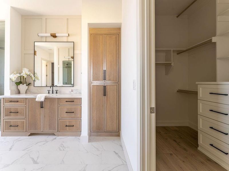 Full bathroom with vanity, light marble finish floors, and a spacious closet