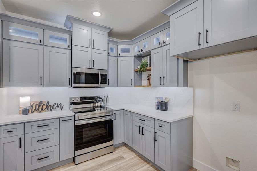 Kitchen featuring gray cabinets, stainless steel appliances, and light hardwood / wood-style flooring