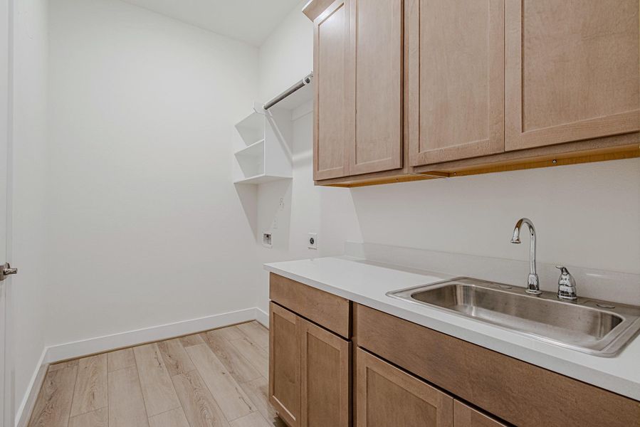 aundry room with cabinetry, utility sink, and workspace.