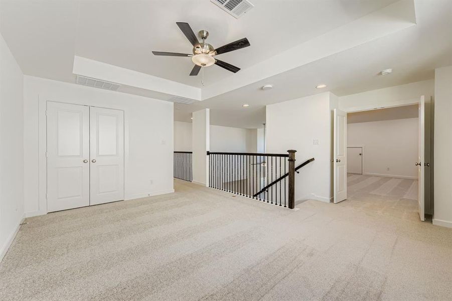 Unfurnished bedroom featuring a raised ceiling, light colored carpet, ceiling fan, recessed lighting, and a closet Unfurnished bedroom featuring a raised ceiling, light colored carpet, ceiling fan, recessed lighting, and a closet