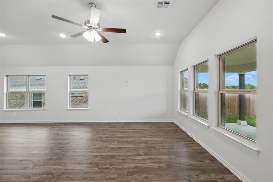 Unfurnished room with a ceiling fan, lofted ceiling, dark wood-type flooring, and visible vents Unfurnished room with a ceiling fan, lofted ceiling, dark wood-type flooring, and visible vents