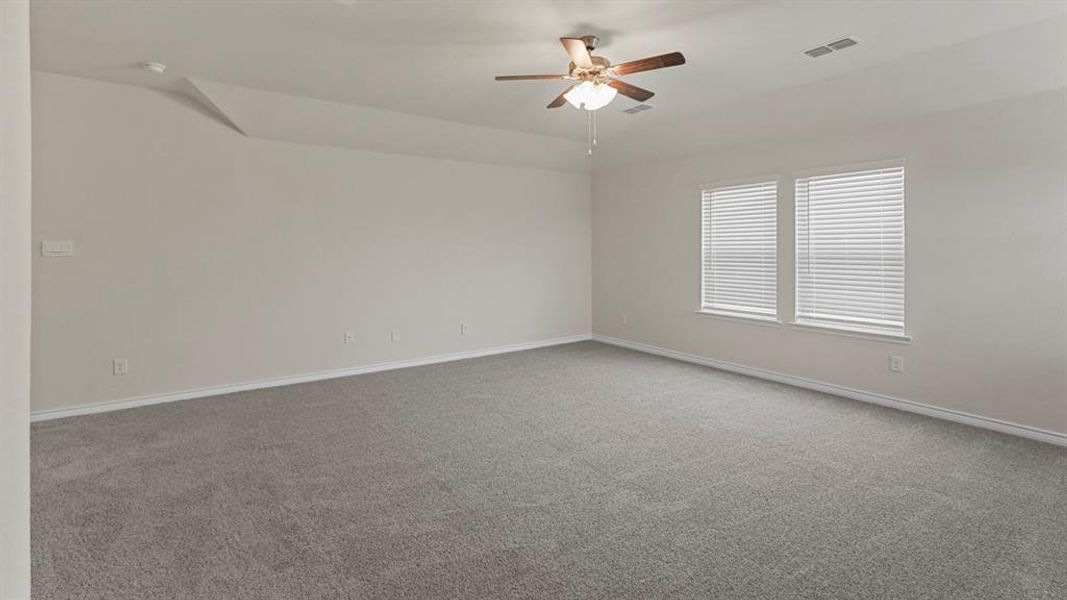 Spacious room featuring neutral carpeting, light-toned walls, and a ceiling fan with integrated lighting