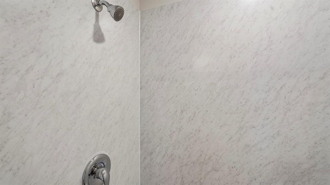 Shower enclosure featuring textured wall panels and polished chrome fixtures