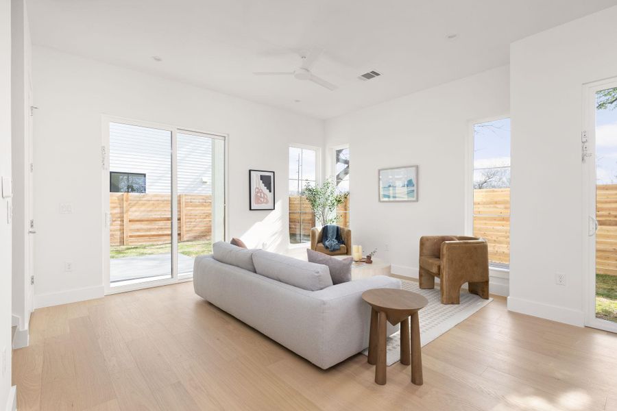 Living room with ceiling fan, light wood-type flooring, and plenty of natural light Living room with ceiling fan, light wood-type flooring, and plenty of natural light