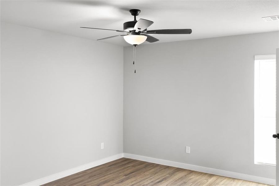 Unfurnished room featuring baseboards, wood finished floors, and a ceiling fan