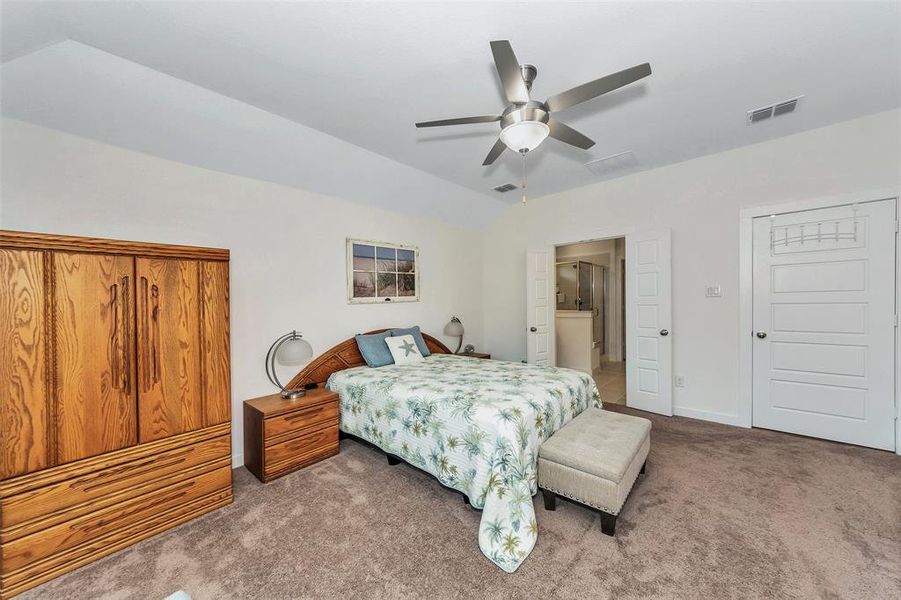 Bedroom featuring ceiling fan, ensuite bath, and light colored carpet