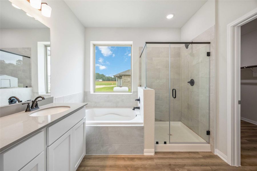 Luxury primary bath with double vanity, soaking tub, walk-in shower, and a generous walk-in closet.