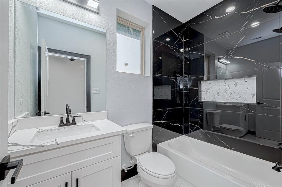 Full bath with a tub-shower combo and quartz countertop, serving one room.