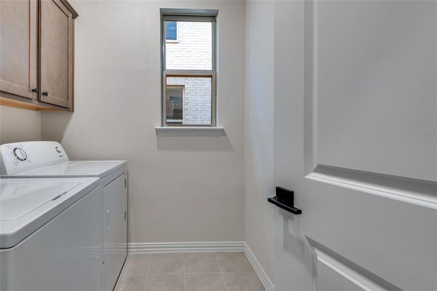 Washroom with washing machine and dryer, cabinet space, and light tile patterned floors