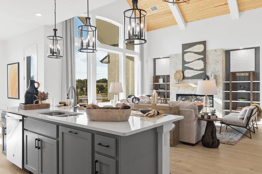 Kitchen featuring a fireplace, gray cabinetry, open floor plan, light wood-style floors, and an island with sink