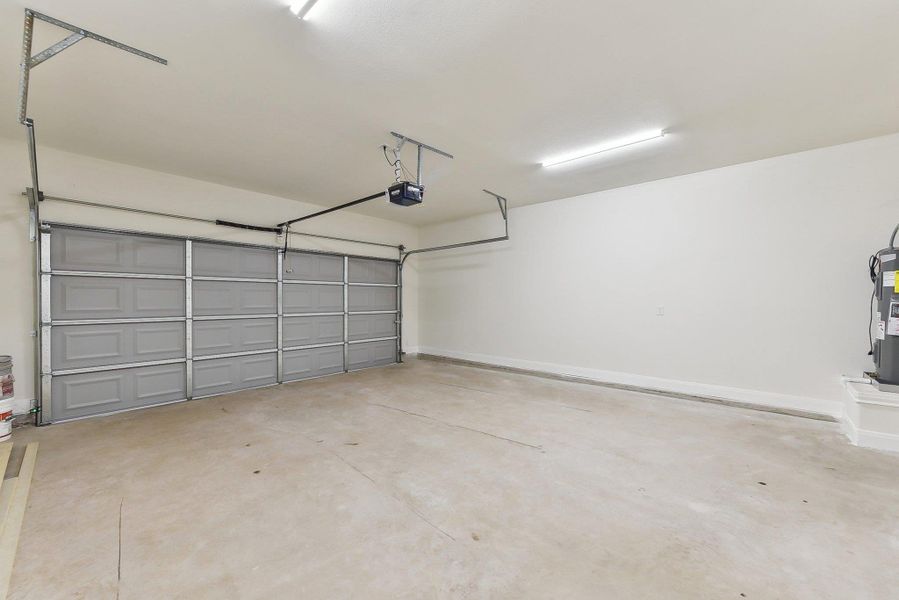 Garage with baseboards, electric water heater, and a garage door opener Garage with baseboards, electric water heater, and a garage door opener