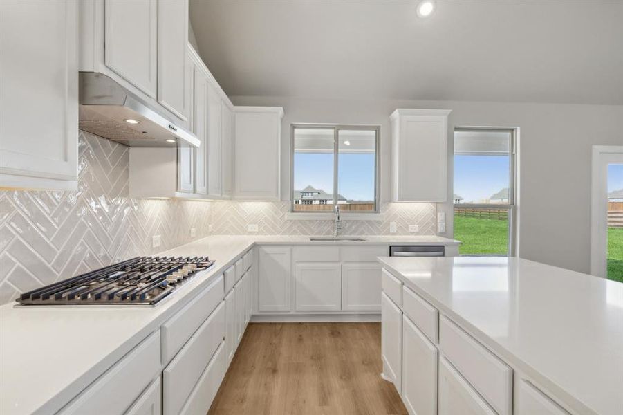 Kitchen featuring appliances with stainless steel finishes, light hardwood / wood-style floors, white cabinetry, and sink