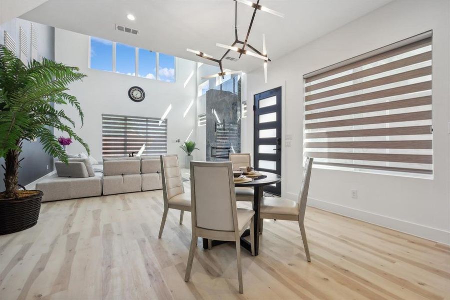 Dining area featuring a towering ceiling, light wood-type flooring, and a chandelier