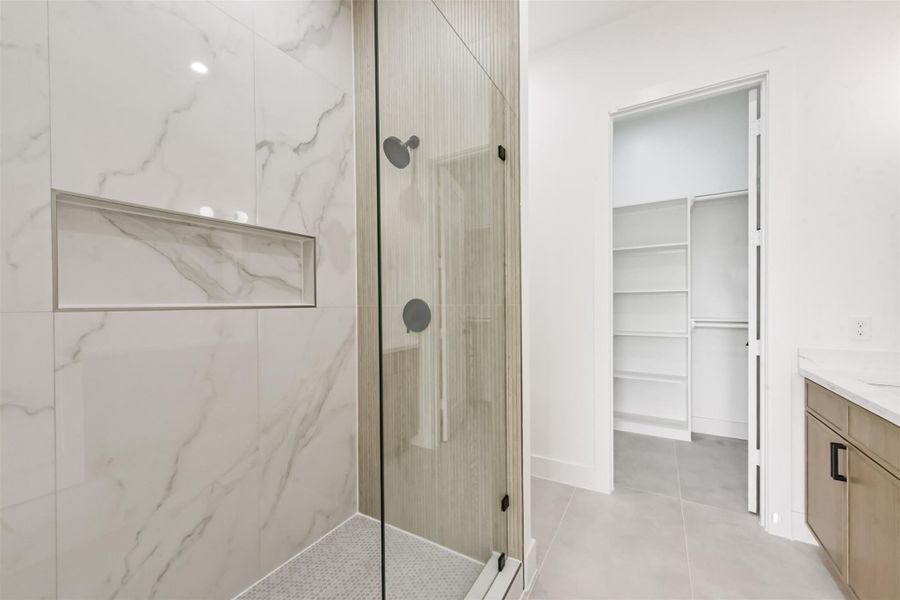The primary bathroom features double sinks, sleek shower, and large closet.