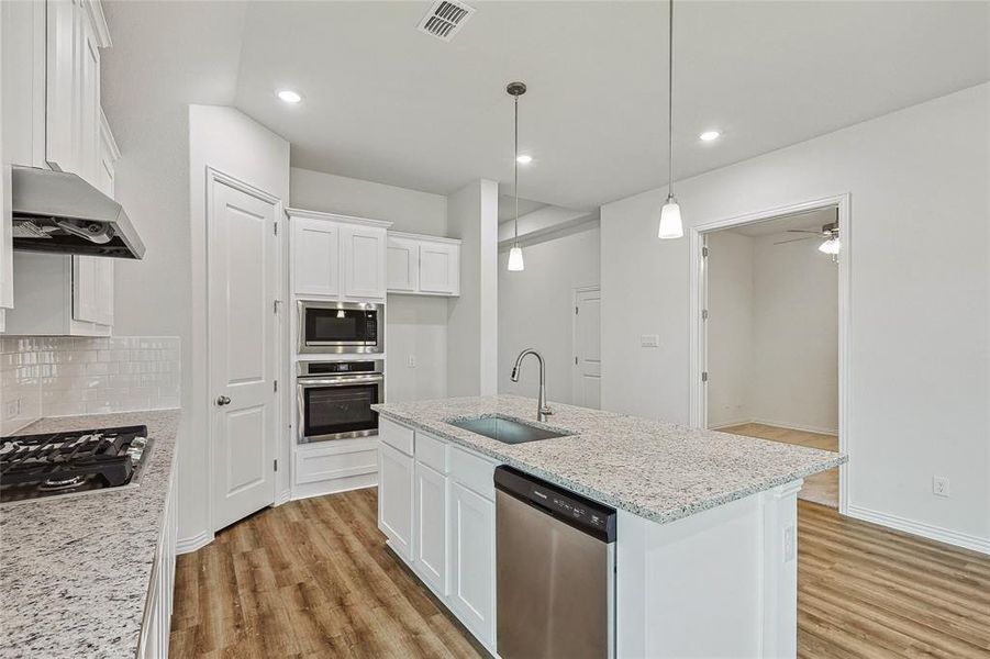 Kitchen with range hood, a center island with sink, light hardwood / wood-style flooring, stainless steel appliances, and sink