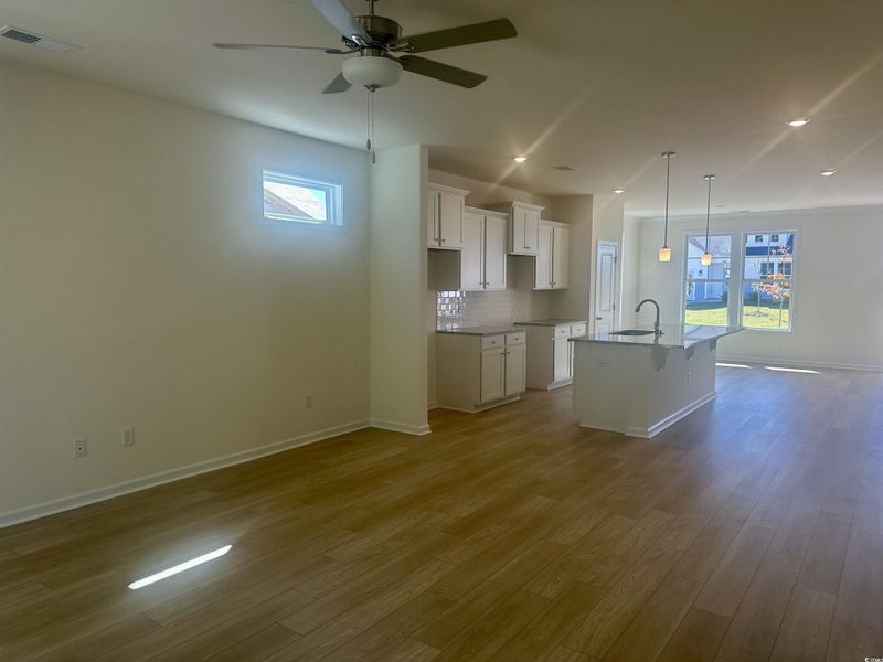 Kitchen with a breakfast bar, open floor plan, backsplash, white cabinets, and pendant lighting Kitchen with a breakfast bar, open floor plan, backsplash, white cabinets, and pendant lighting