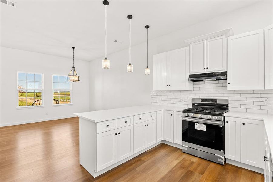 Modern kitchen featuring white shaker cabinetry, quartz countertops, a new stainless steel gas range, and subway tile backsplash