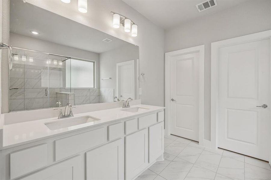 Bathroom with double vanity, a shower stall, and light marble finish flooring Bathroom with double vanity, a shower stall, and light marble finish flooring