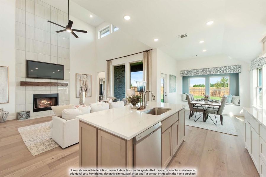 Open-concept living area with kitchen island, fireplace, dining space, and high ceilings with ceiling fan