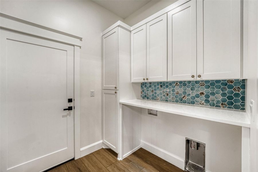 Even the laundry room is gorgeous with contemporary cabinetry, a vanity area, and chic tile back plash.