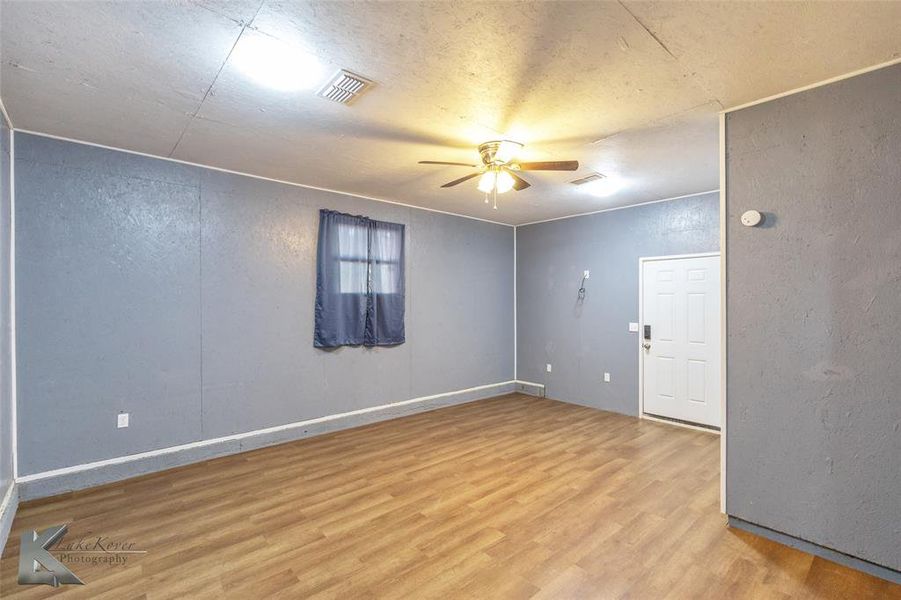 Unfurnished room with a textured wall, wood finished floors, a ceiling fan, and a textured ceiling