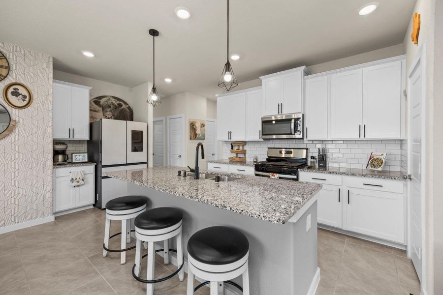 This spacious and modern kitchen is an entertainer's dream. It's equipped with stainless steel appliances, crisp white cabinetry, and granite countertops. The large center island provides a great space for cooking or gathering, with plenty of room for seating.