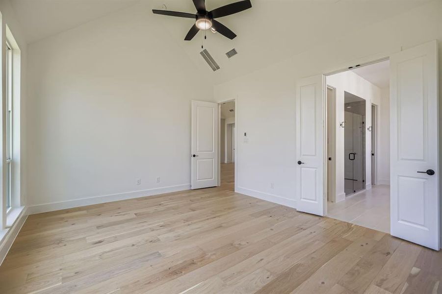 Unfurnished bedroom featuring light wood-style floors, high vaulted ceiling, and a ceiling fan
