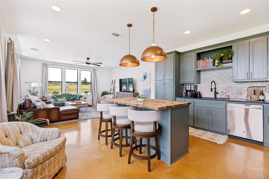Open-concept living space featuring a spacious kitchen island with seating, pendant lighting, stainless steel appliances, and ample cabinetry Open-concept living space featuring a spacious kitchen island with seating, pendant lighting, stainless steel appliances, and ample cabinetry
