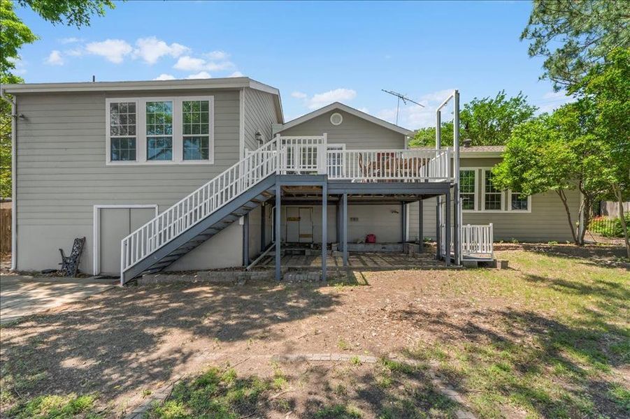 Rear view of house with a wooden deck and a patio
