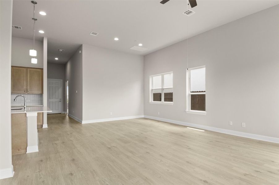 Unfurnished living room featuring a ceiling fan, light wood-style floors, recessed lighting, baseboards, and a sink