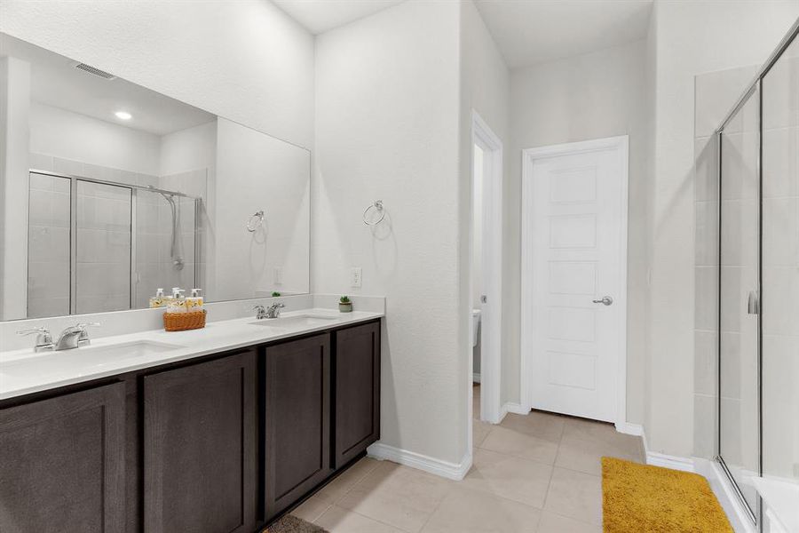 Full bathroom with a shower stall, tile patterned floors, double vanity, and a sink
